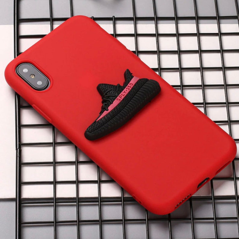 Puede incluir: Funda de tel&eacute;fono roja con un dije de zapato 3D negro y rojo adherido a la parte posterior. El dije de zapato dice "SPLY-350".