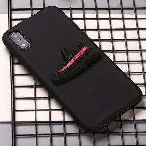 Puede incluir: Funda de tel&eacute;fono negra con un dise&ntilde;o de zapatilla 3D roja y negra. La zapatilla tiene el texto "SPLY-350" en el lateral.