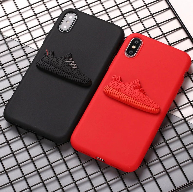 Puede incluir: Dos fundas para tel&eacute;fono con un dise&ntilde;o de zapato 3D. Una funda es negra con un zapato negro y la otra funda es roja con un zapato rojo.