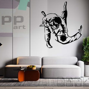 May include: Black and white silhouette of two people in a judo or jiu-jitsu hold. The image is on a white wall in a living room setting with a grey sofa and a black floor lamp.