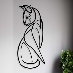 May include: Black metal wall art sculpture of a stylised cat in a sitting pose.
