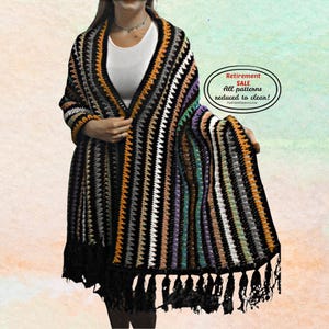 Könnte beinhalten: Ein bunt gestreifter Häkelschal mit schwarzem Fransen. Der Schal hat vertikale Streifen in verschiedenen Farben, darunter Schwarz, Orange, Weiß, Grau, Lila und Grün. Der Text auf dem Bild lautet "Retirement SALE All patterns reduced to clear!"