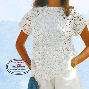 May include: A white, short-sleeved crochet top with a floral pattern. The top has a round neckline and a loose fit. The image includes text that reads "Retirement SALE All patterns reduced to clean!" and "FashionPatternLove".