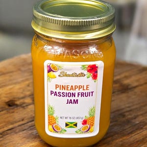 May include: A jar of Pineapple Passion Fruit Jam with a gold lid and a white label. The label features the text "Shantastic" and "Pineapple Passion Fruit Jam". The jar contains 453 g of jam and is set on a wooden surface.