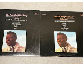 May include: Two black vinyl record album covers titled The Nat King Cole Story Volume 1 and Volume 2, His All-Time Great Performances. Each cover features a portrait of Nat King Cole wearing a light-colored coat against a light blue sky background.
