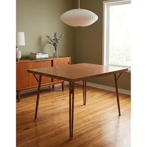 May include: A rectangular wooden dining table with a smooth, medium-brown finish and four slender, tapered legs. The table features a clean, flat surface and a simple frame design, providing a stable base for dining or workspace needs in a room.