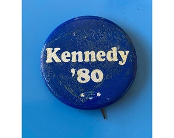 May include: A blue button with white text that reads "Kennedy '80".
