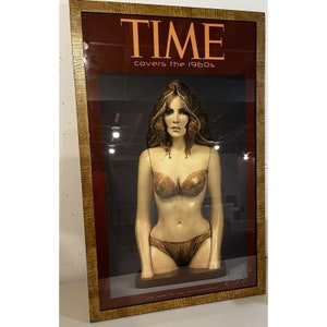 May include: A framed print of a TIME magazine cover featuring a woman in a brown bikini. The cover text reads "TIME covers the 1960s".