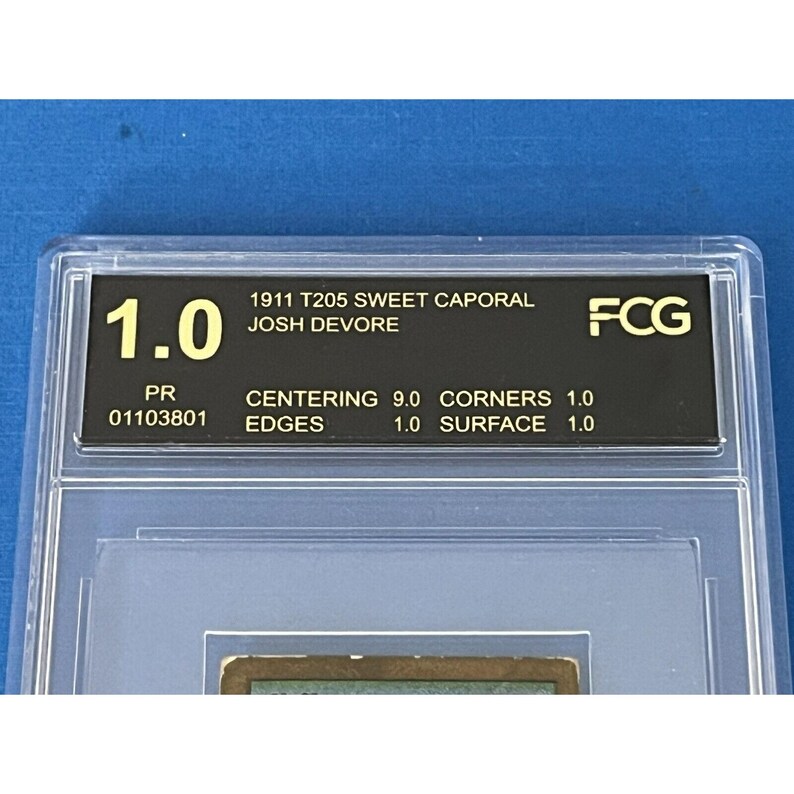 K&ouml;nnte beinhalten: Eine bewertete Baseballkarte in einem Schutzgeh&auml;use. Die Karte ist eine 1911 T205 Sweet Caporal von Josh DeVoire. Die Karte ist mit 1.0 vom FCG bewertet. Die Karte befindet sich in einem Schutzgeh&auml;use mit schwarzem Hintergrund und goldenen Schriftz&uuml;gen. Die Karte ist mit 9.0 f&uuml;r die Zentrierung, 1.0 f&uuml;r die Ecken, 1.0 f&uuml;r die Kanten und 1.0 f&uuml;r die Oberfl&auml;che bewertet.