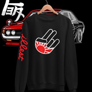 May include: Black sweatshirt with a white hand gesture graphic and a red rising sun design. The text "illest" is written in red on the left sleeve.