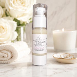 May include: A cylindrical pump bottle of Nourishing Complexion Balm Adaptive Coverage Foundation in Untinted. The white label features a butterfly icon and states Net Wt 1 oz (28.35 g) and the brand name Reinvigoratedesigns.com.