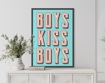 May include: A framed print with a turquoise background and the text "BOYS KISS BOYS" in a retro, 3D-style font. The letters are outlined in red and filled with a light peach color.