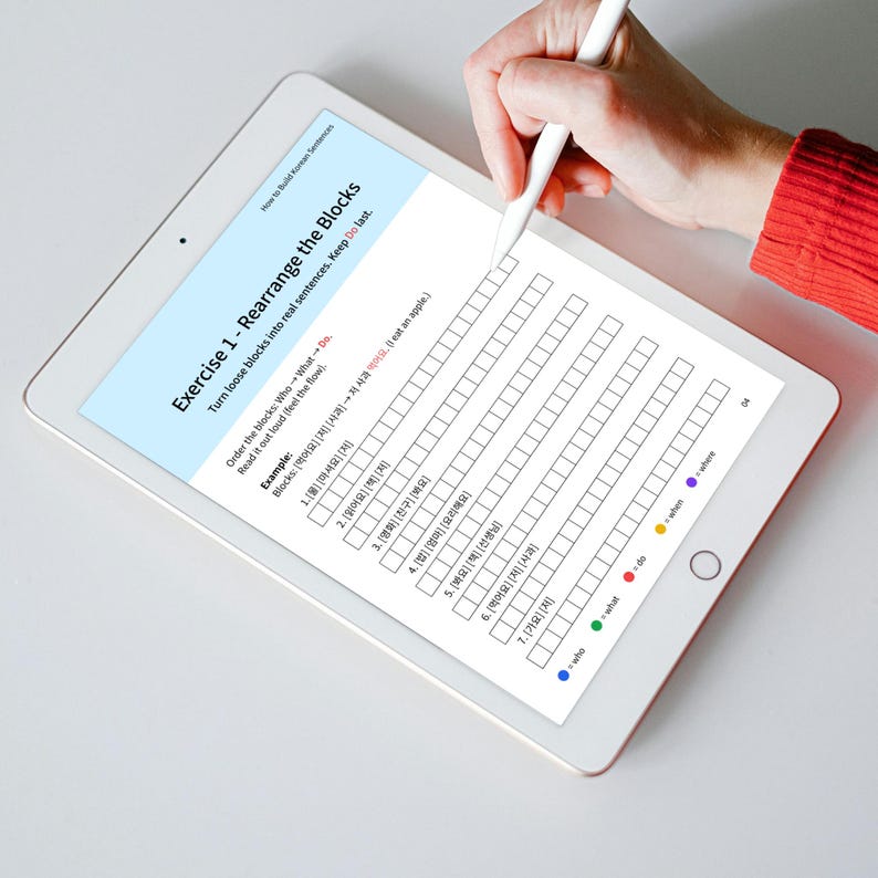 A white tablet displays a Korean language exercise titled 'Rearrange the Blocks.' The exercise involves rearranging blocks of words to form sentences, with instructions and an example provided. A hand holding a white stylus hovers over the tablet's screen, ready to interact with the digital worksheet. Color-coded labels for 'who,' 'what,' 'do,' and 'where' are at the bottom.