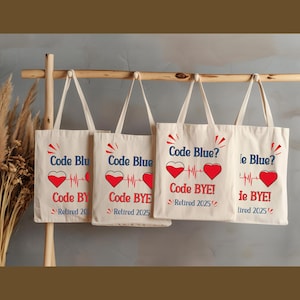May include: Four white tote bags with red hearts and blue text. The text on the bags reads "Code Blue? Code BYE! Retired 2025".