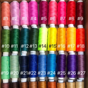 May include: A collection of 44 spools of thread in various colors, numbered 1 through 44. The spools are arranged in rows of nine, with the exception of the last row, which has only five spools.