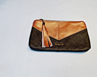 May include: A black and gold zippered pouch with a tassel. The pouch has a geometric design with a gold section in the center and black sections on either side.