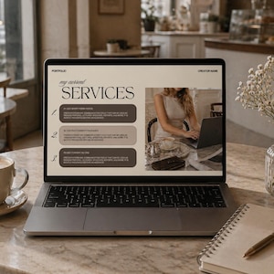 May include: A laptop displaying a portfolio with the text "my current SERVICES" and a woman working on it. A cup of coffee, a notebook, a pen, and a vase of flowers are on the table. The laptop screen shows a list of services.