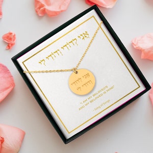 May include: A gold necklace with a round pendant featuring Hebrew text. The pendant reads "אני לדודי ודודי לי" which translates to "I am my beloved's and my beloved is mine." The necklace is in a black box with a white background and the text "I am my beloved's and my beloved is mine" is written below the pendant.