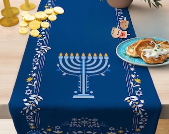 May include: Blue table runner with a white floral pattern and a menorah design. The runner also features gold coins and dreidels.