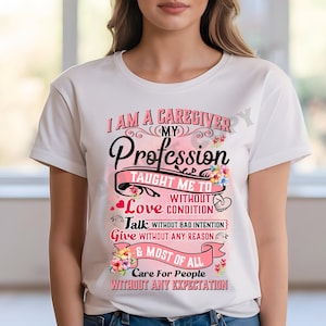 May include: White t-shirt with the text "I AM A CAREGIVER" and "My Profession Taught Me To..." in pink and black. Floral and heart accents decorate the design. The shirt is a crew neck style.