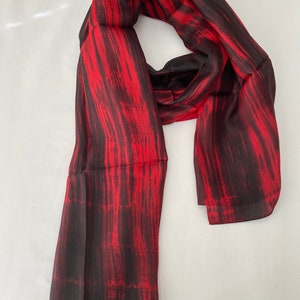 May include: A red and black silk scarf with a tie-dye pattern.