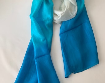 May include: A long, flowing scarf with a gradient of blue and white colors. The scarf is made of a soft, silky material and has a delicate, flowing drape.