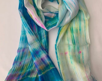 May include: A light blue silk scarf with a tie-dye pattern in shades of green, yellow, and pink.