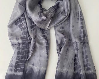 Op de afbeelding: Een grijze zijden sjaal met een tie-dye patroon. De sjaal heeft een kleurverloop van lichtgrijs naar donkergrijs.