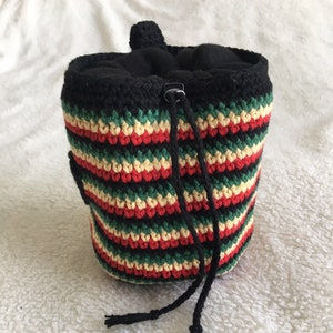 May include: A black, green, red and cream striped crocheted drawstring bag with a black lining and a black drawstring.