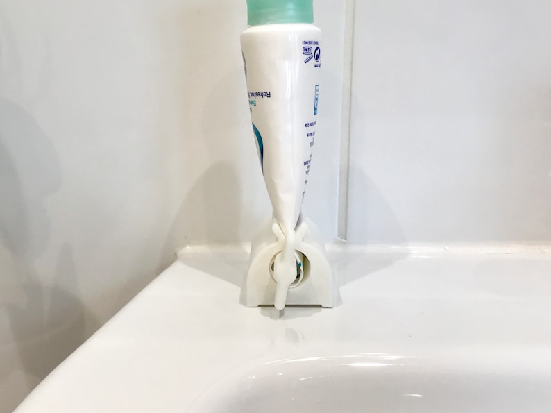 May include: White plastic tube squeezer with a blue and white tube of hand cream inserted. The tube is labeled "Refreshing Body Lotion".