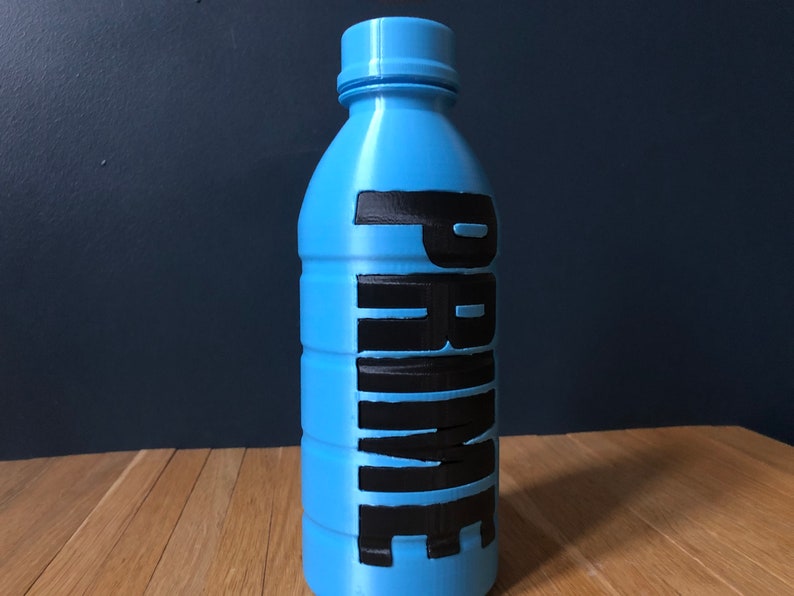 Op de afbeelding: Een blauwe plastic fles met het woord "PRIME" in zwarte letters.