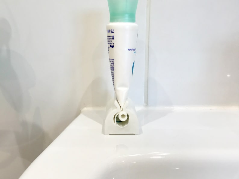 May include: White plastic tube holder with a white tube of lotion inside. The holder has a hole in the bottom to dispense the lotion.
