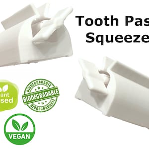 May include: Two white plastic toothpaste squeezers. The squeezers are designed to help get the last bit of toothpaste out of the tube. The image also includes three green labels that say "Plant based", "Biodegradable", and "Vegan".