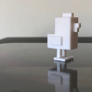 Op de afbeelding: Een wit 3D-geprint model van een gestileerde kip. De kip heeft een blokvormig ontwerp met een kleine snavel en poten.