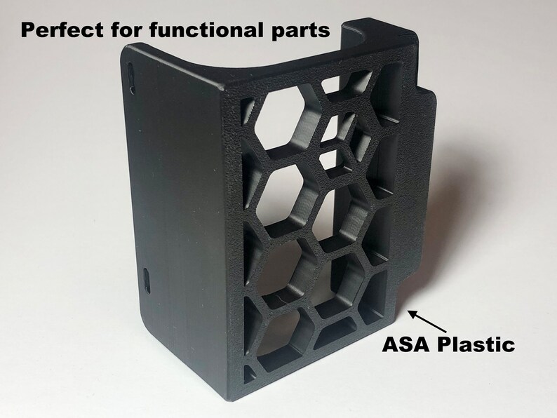 Op de afbeelding: Een zwart kunststof onderdeel met een honingraatpatroon. De tekst "ASA Plastic" staat onder het onderdeel.