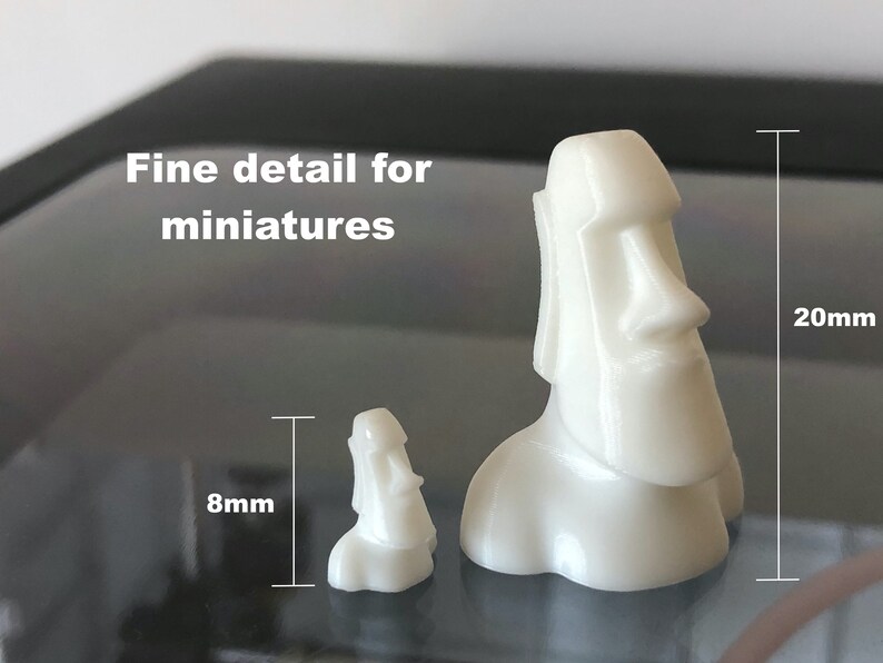 Op de afbeelding: Twee witte 3D-geprinte miniatuurbeeldjes van Paaseilandhoofden. Het grotere beeldje is 20 mm hoog en het kleinere beeldje is 8 mm hoog.  Fijne details voor miniaturen.