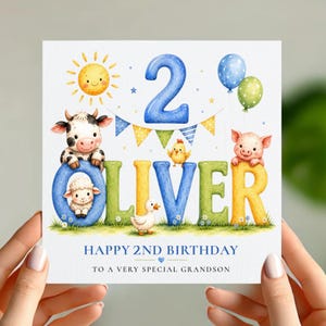 Può includere: Un biglietto d'auguri quadrato con un grande numero 2 blu, un sole giallo e palloncini blu e verdi. Il nome OLIVER è scritto con lettere colorate e illustrazioni di una mucca, una pecora, un pulcino e un'anatra. Testo: HAPPY 2ND BIRTHDAY TO A VERY SPECIAL GRANDSON.