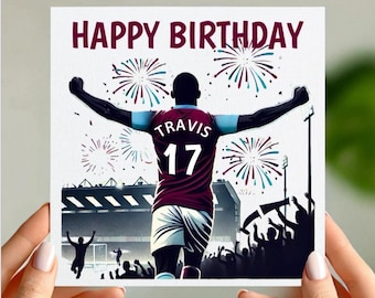 May include: A birthday card featuring a cartoon illustration of a soccer player celebrating a goal with fireworks in the background. The player is wearing a maroon and blue jersey with the name "Travis" and the number "17" on the back. The card says "Happy Birthday" at the top.