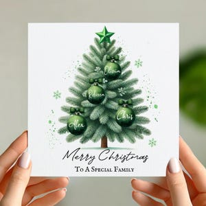 May include: A green Christmas tree with ornaments that have names on them. The names are Alex, Chris, Olivia, and Rebecca. The text at the bottom of the card says "Merry Christmas to a special family".