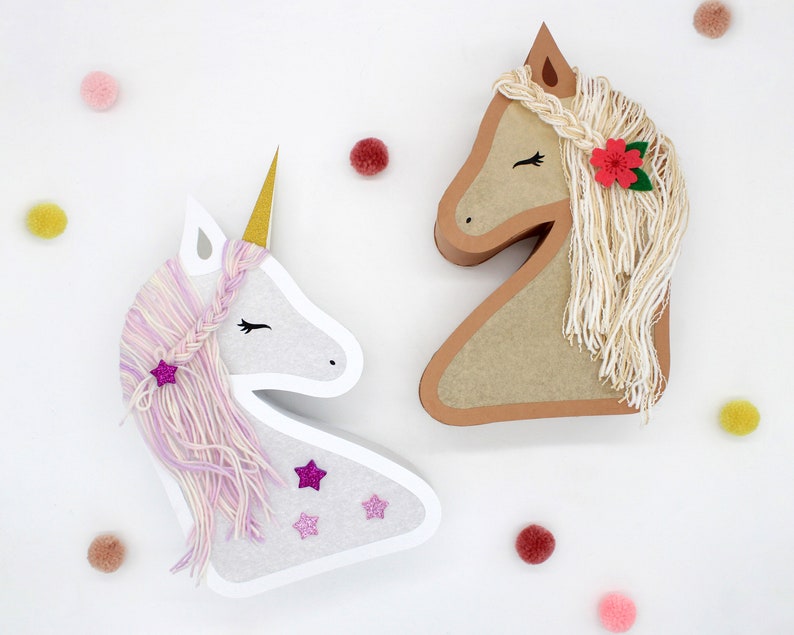 May include: Two paper mache animal head decorations. A white unicorn with a pink and purple yarn mane and a brown horse with a white yarn mane. Both have glitter stars and flowers.