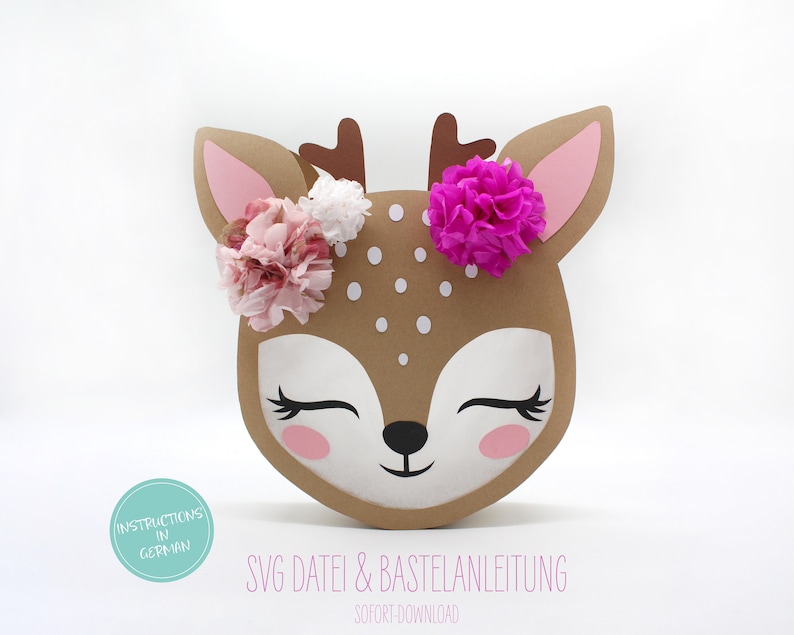 May include: A brown paper deer head with pink and white tissue paper flowers, black eyes, and a white nose. The deer head has white polka dots and the text "SVG DATEI & BASTELANLEITUNG SOFORT DOWNLOAD" is below the deer head.