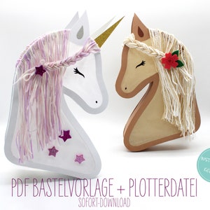 May include: Two papercraft unicorn heads, one white with pink yarn hair and the other brown with white yarn hair. The white unicorn has a gold horn and pink glitter stars. The brown unicorn has a red felt flower. The text "PDF Baste Vorlage + Plotterdatei" and "SOFORT-DOWNLOAD" is at the bottom of the image. A circle with the text "Instructions in German" is in the lower right corner.