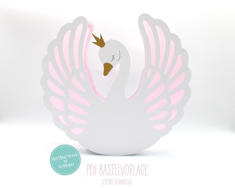 May include: A white papercraft swan with pink wings and a gold crown. The swan is standing on a white surface. The text "PDF Bastevorlage" and "Sofort Download" is printed below the swan.