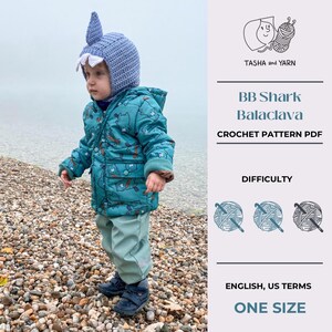 May include: A crochet pattern for a baby shark balaclava, with a difficulty rating of three yarn balls. The pattern is written in English using US terms and is for one size.