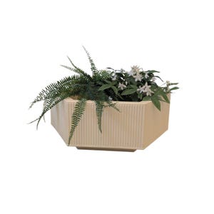 Könnte beinhalten: Ein rechteckiger, cremefarbener Pflanzkübel mit vertikalen Rippendetails. Der Pflanzkübel ist mit grünen Farnen und weißen Blütenpflanzen gefüllt. Der Pflanzkübel hat eine geometrische Form und steht vor einem weißen Hintergrund.