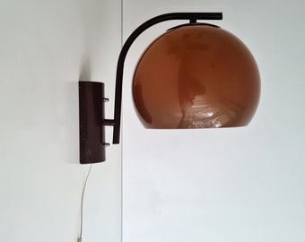 May include: A wall-mounted light fixture with a brown, spherical shade and a dark brown metal arm. The fixture is attached to a wall with a matching dark brown base. A pull cord hangs below.
