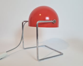 May include: A red and chrome table lamp with a round shade and a square base.