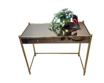 Consola vintage estilo Hollywood Regency de latón con tapa de cristal ahumado espejado y cajones.
