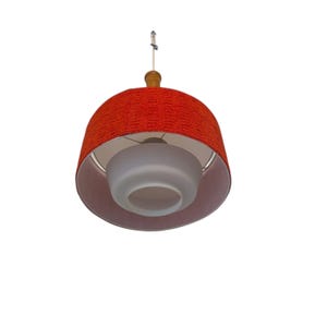 May include: A vintage pendant light fixture with a red textured shade and a frosted glass diffuser. The light has a wooden top and is suspended by a white cord. The fixture is designed to hang from the ceiling.