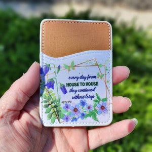 May include: A white card holder with a floral design and a gold frame. The card holder has a quote from the Bible, Acts 5:42, that reads "every day from house to house they continued without letup".